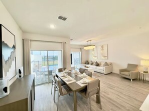 Ein modernes Wohnzimmer mit Essbereich, einer Sofagarnitur und Blick auf einen Balkon.