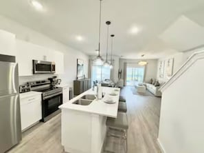 A modern kitchen with stainless steel appliances, a central island, and pendant lighting.