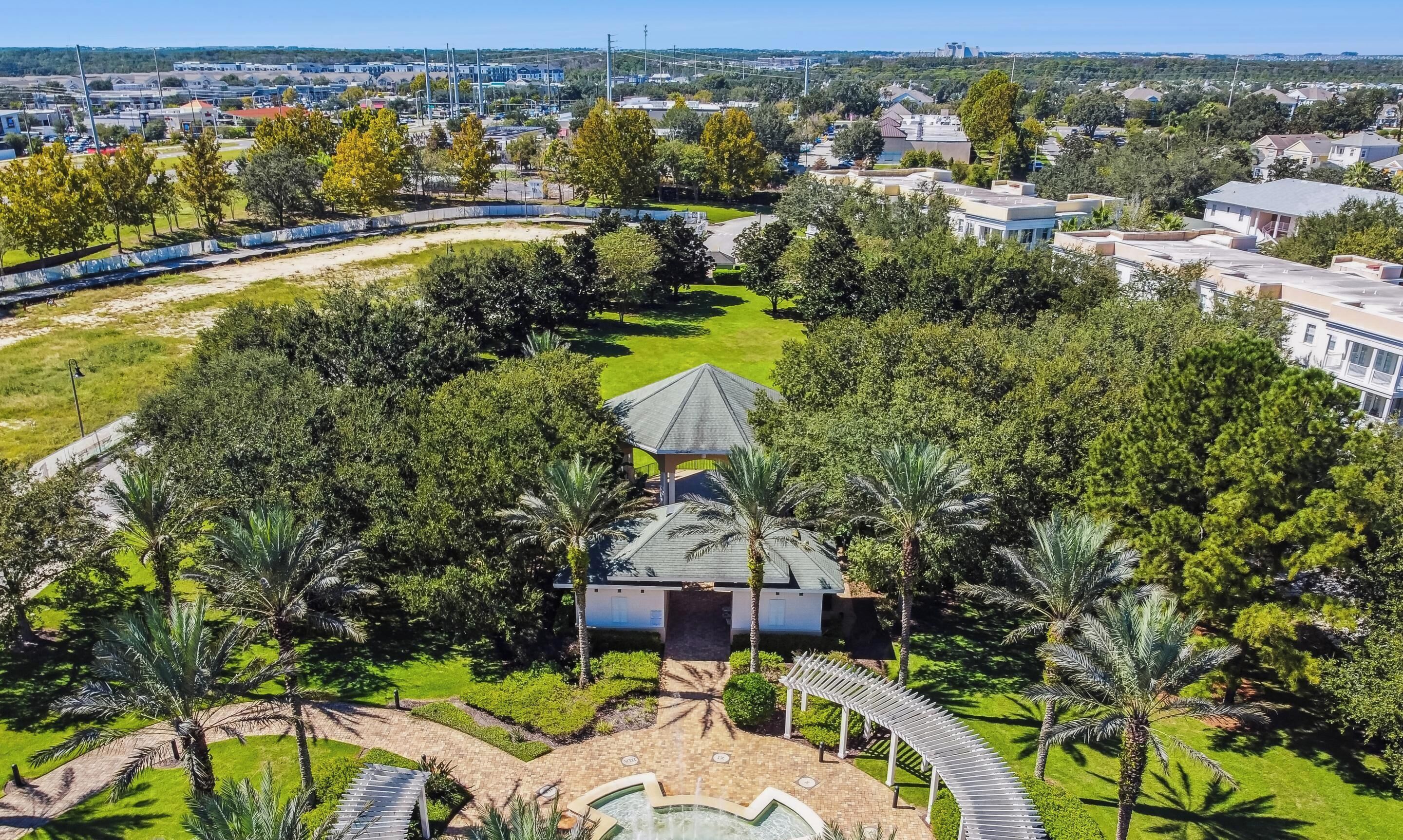 An aerial view of a resort with a pool, palm trees, and a gazebo.