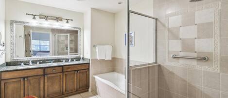 A bathroom with a vanity, a bathtub, and a shower area.