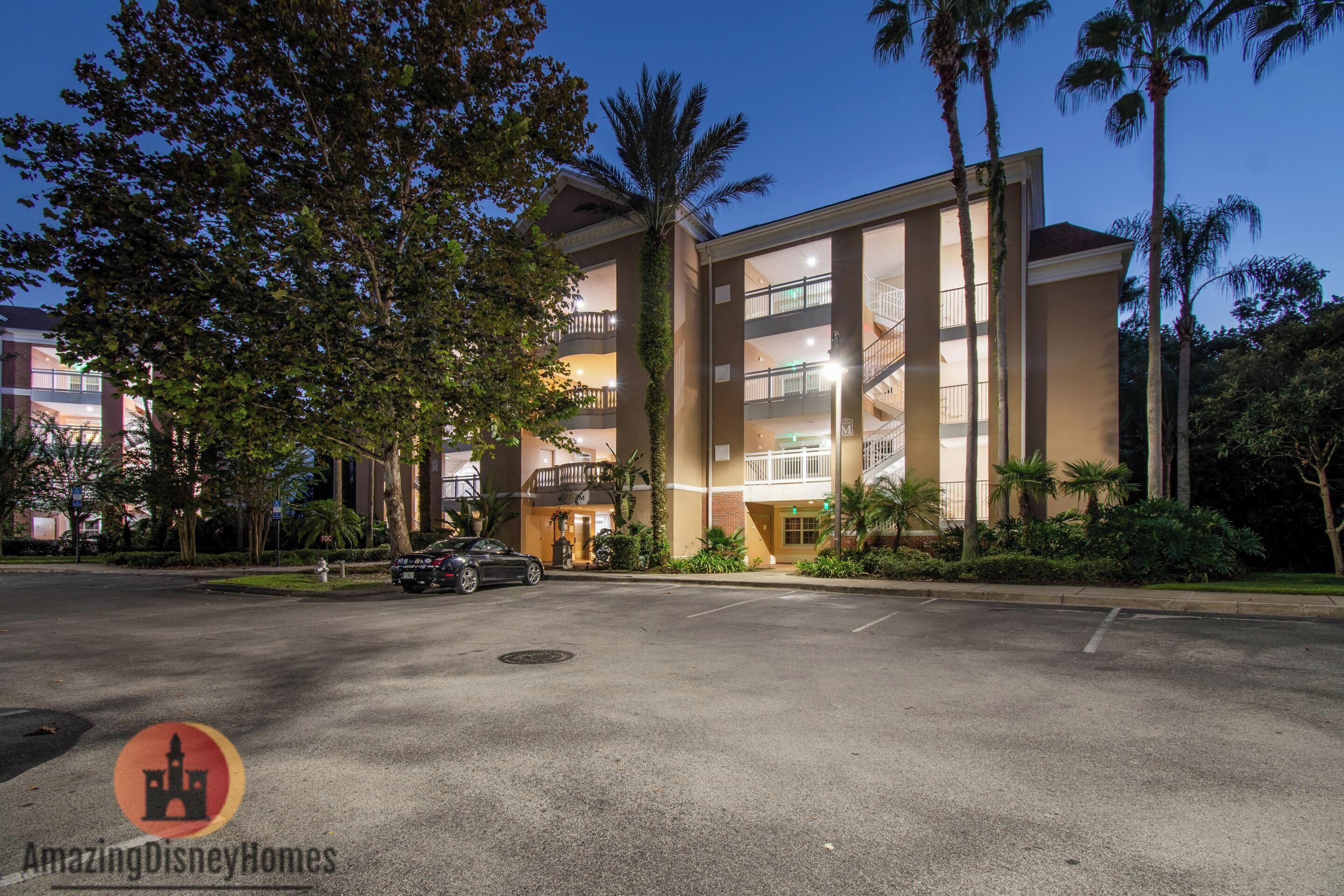 A multi-story building with a central atrium, surrounded by palm trees and a parking lot.