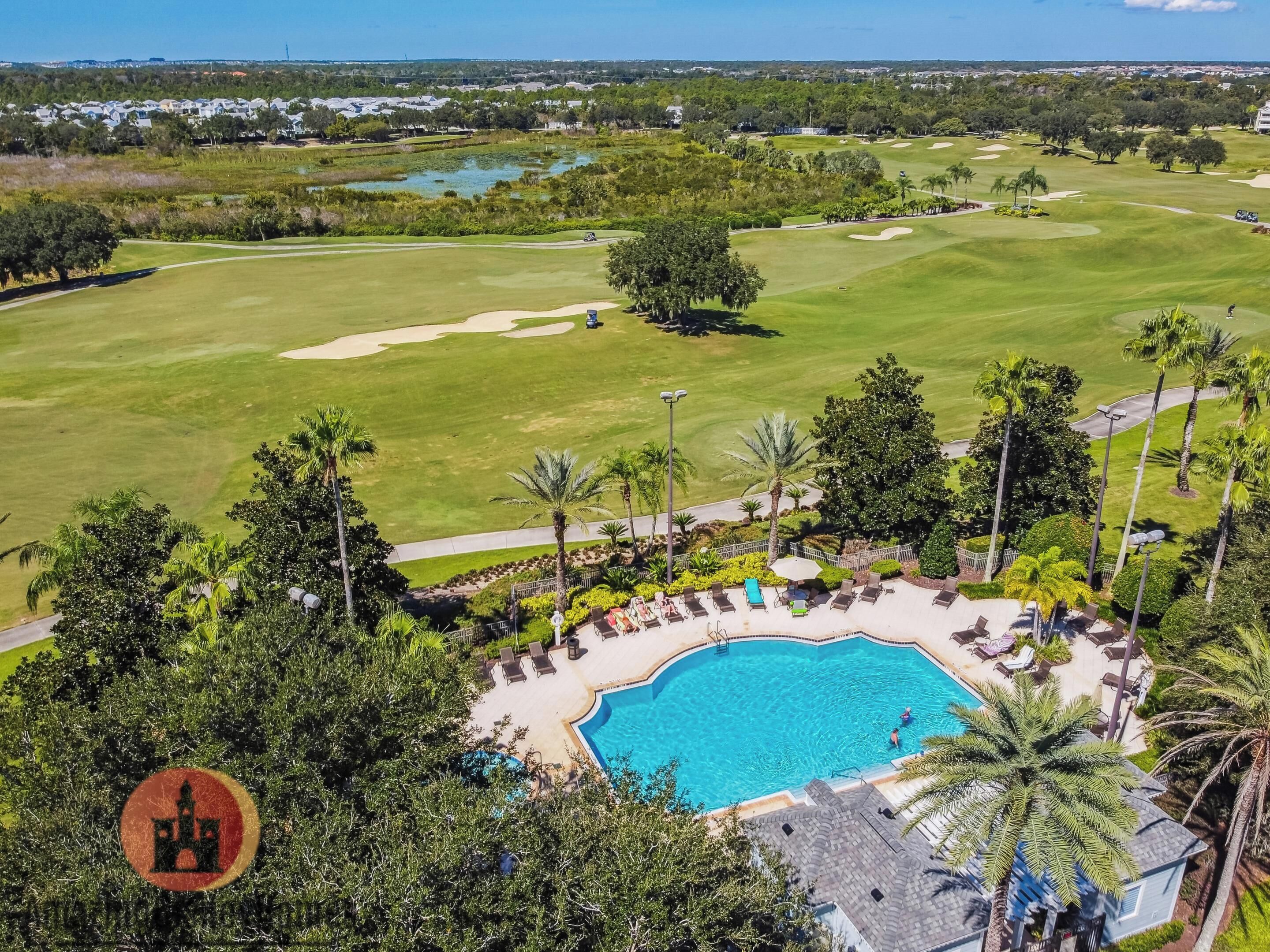 Ein Golfplatz mit Schwimmbad und Liegebereich, umgeben von Palmen.
