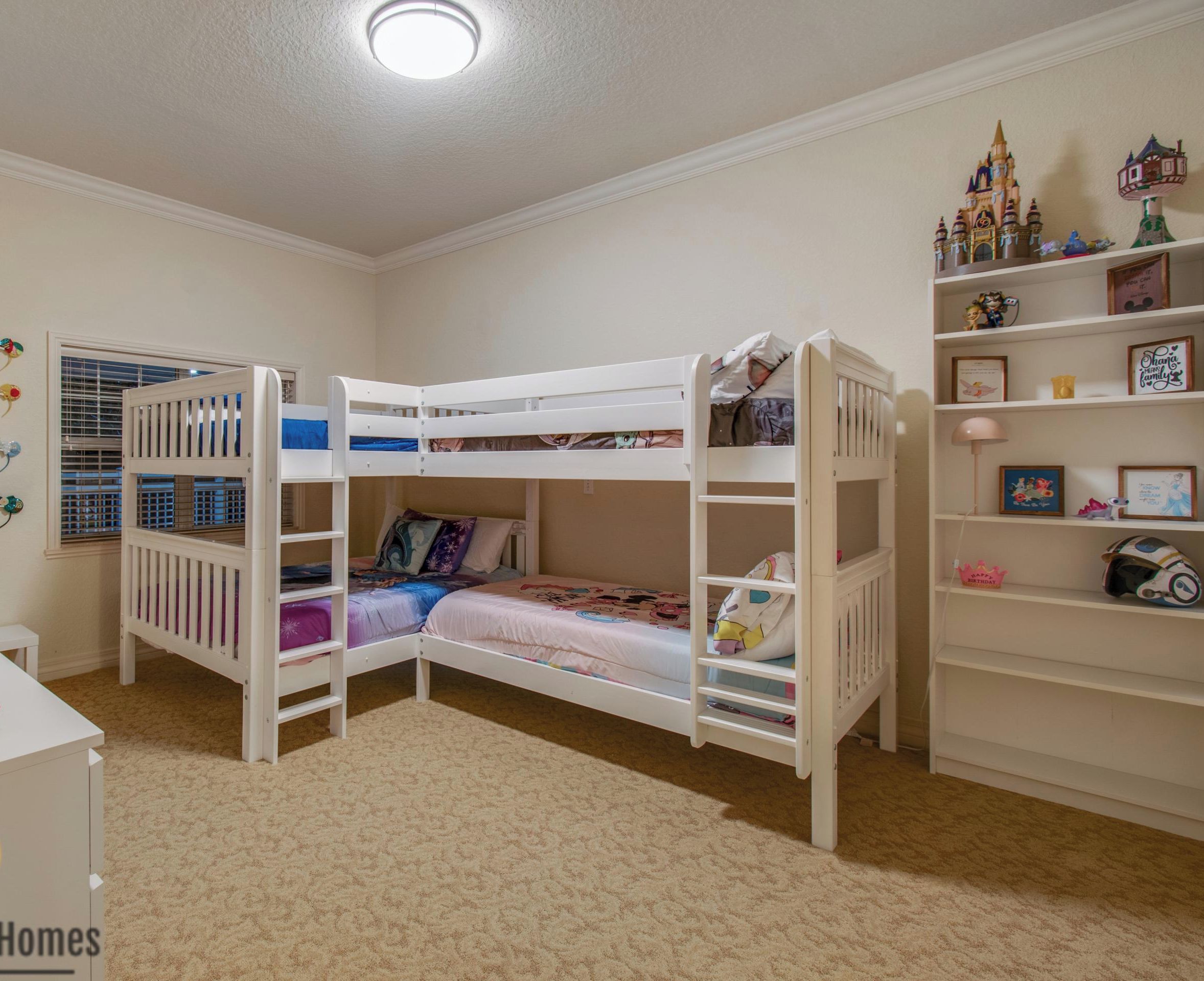 A child's bedroom with bunk beds, a desk, and shelves with Disney-themed decorations.