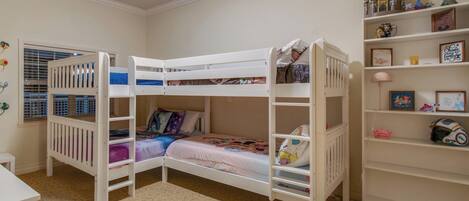 A child's bedroom with bunk beds, a desk, and shelves with Disney-themed decorations.