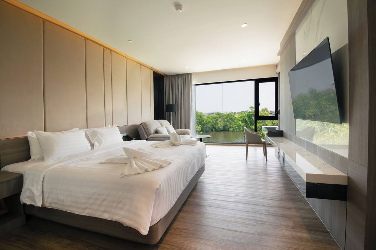 Ein modernes Hotelzimmer mit einem großen Bett, einem Fernseher, einem Balkon mit Blick und einem Schreibtisch.