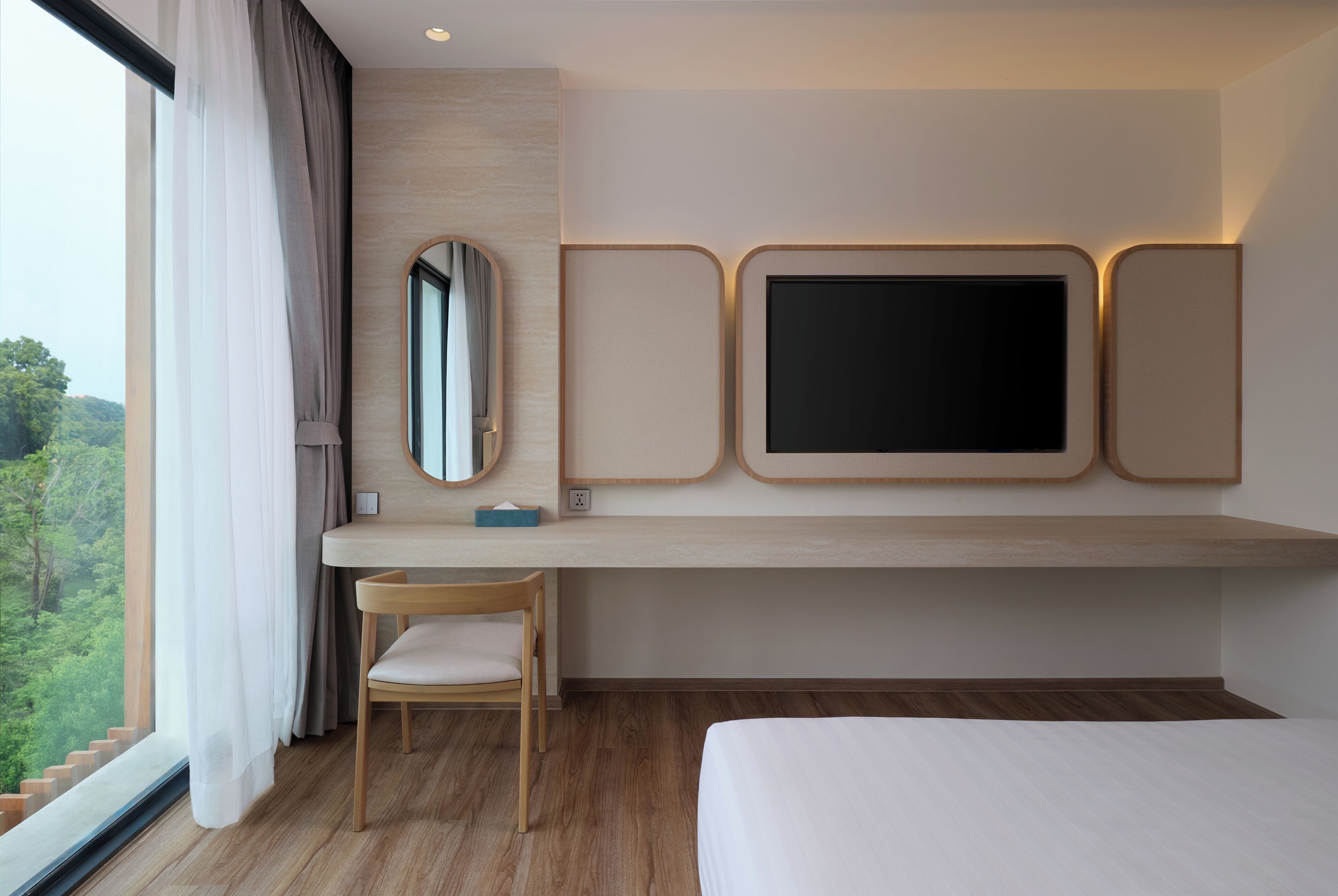 Habitación de hotel con cama, escritorio con silla, un espejo grande y televisor montado en la pared.