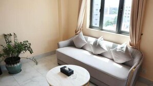 A living room with a sofa, a round coffee table, and a potted plant.