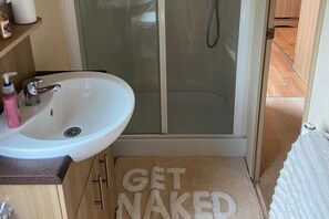 A bathroom with a white sink, a glass shower enclosure, and a towel rack. - 2 Bed Caravan-sleeps 6-pet Friendly (Carnforth)