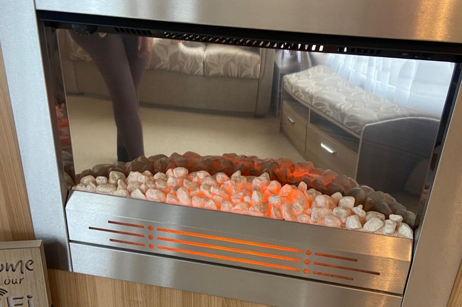 A room with a bed, a nightstand, and a heater with glowing stones.
