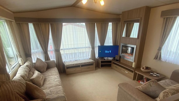 A spacious living area with a sofa set, a flat-screen TV, and a fireplace. - 2 Bed Caravan-sleeps 6-pet Friendly (Carnforth)