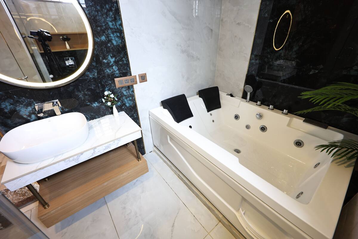 Un baño moderno con una bañera blanca, un espejo grande y un respuesto de mármol.