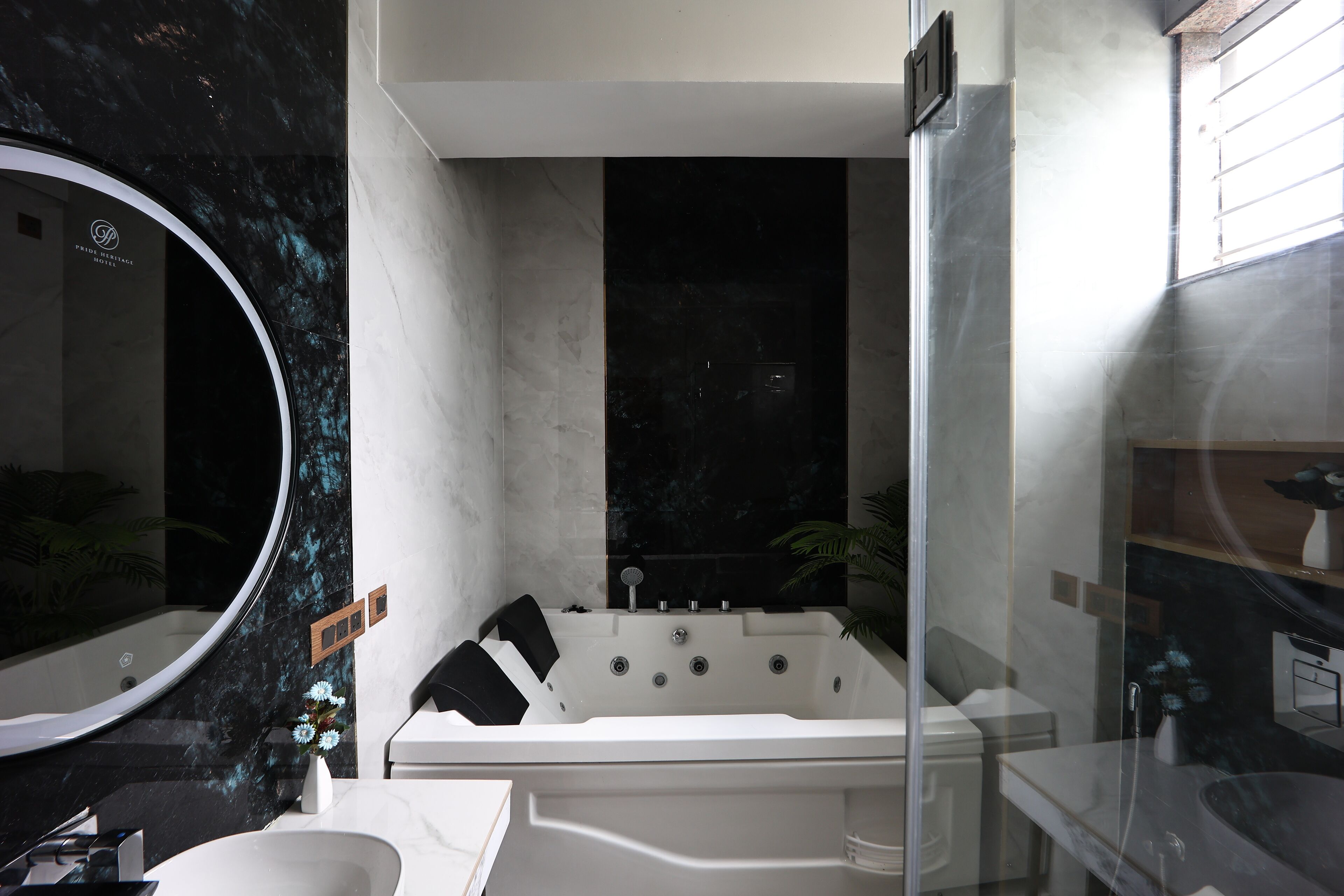 Un baño moderno con una bañera independiente, un espejo grande y una planta en maceta.