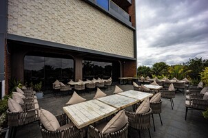 Un patio al aire libre con mobiliario de mimbre y un muro de ladrillo.