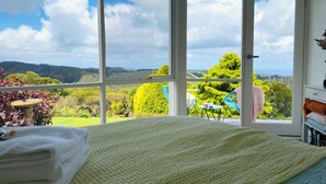Un dormitorio con un ventanal que ofrece vistas de un paisaje verde exuberante y colinas.