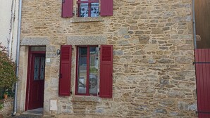 Un bâtiment en pierre doté de deux fenêtres, chacune ornée de volets rouges.