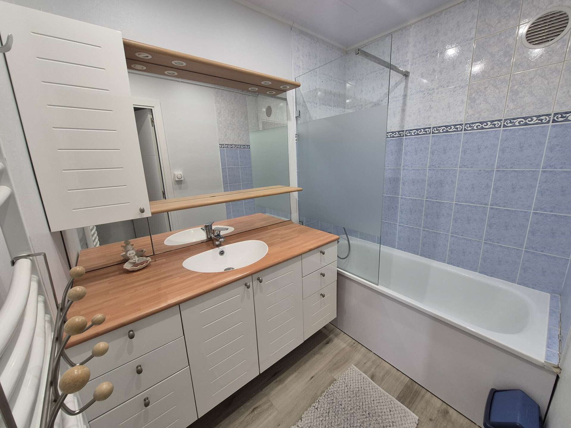 A bathroom with a wooden vanity, two sinks, a mirror, a shower enclosure, and a bathtub.