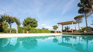 A clear blue pool with a pergola and seating area, surrounded by lush greenery and trees. - Villa San Donato (Rignano sull'Arno)