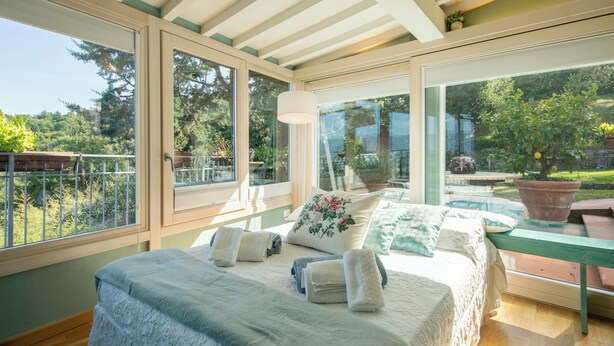 A bedroom with a large bed, a view of the garden, and a glass door leading outside. - Villa San Donato (Rignano sull'Arno)