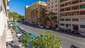 Un edificio de varios pisos con una fila de coches estacionados a lo largo de la calle.