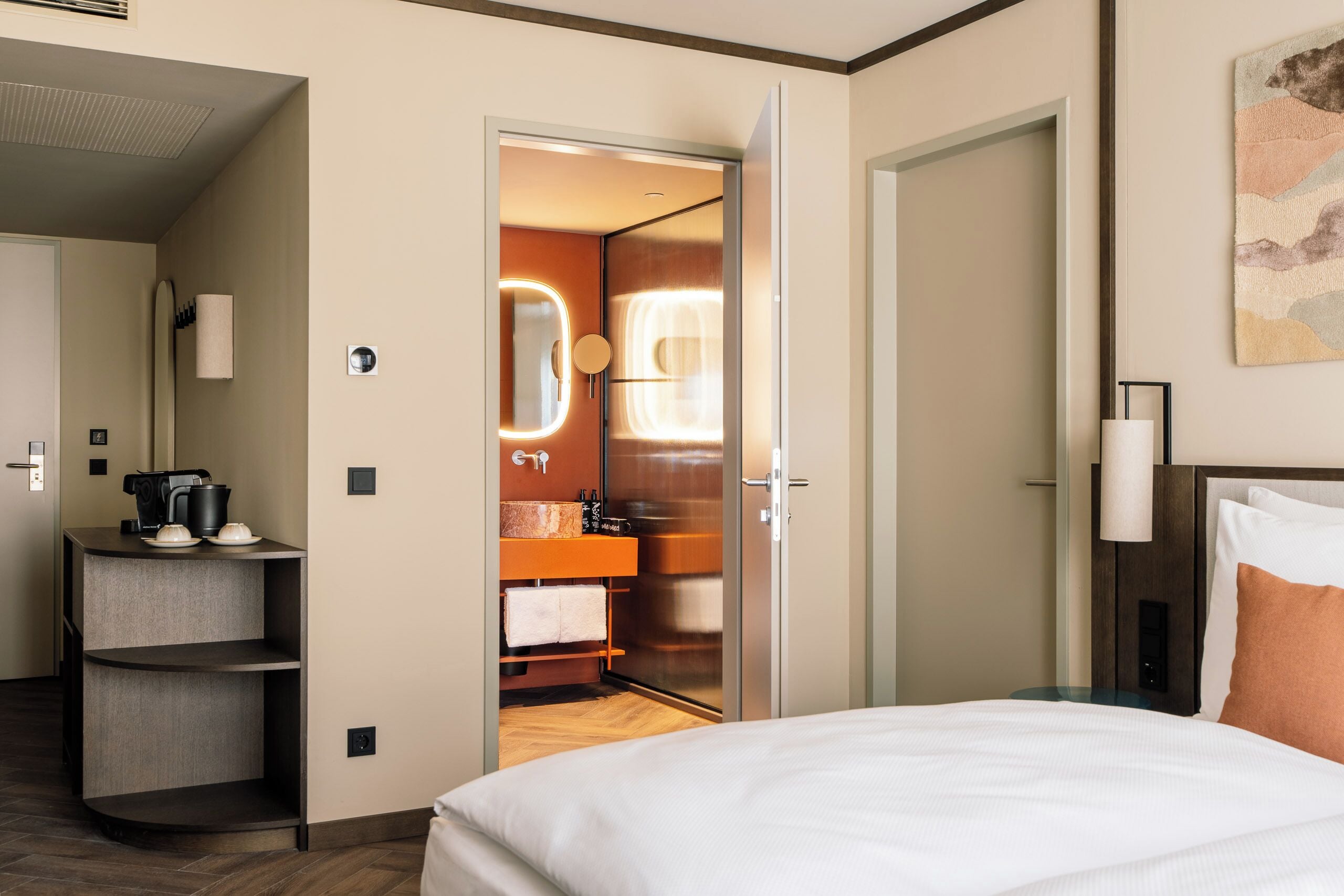 Et hotelværelse med en seng, et badeværelse med et spejl og et tekøkken.