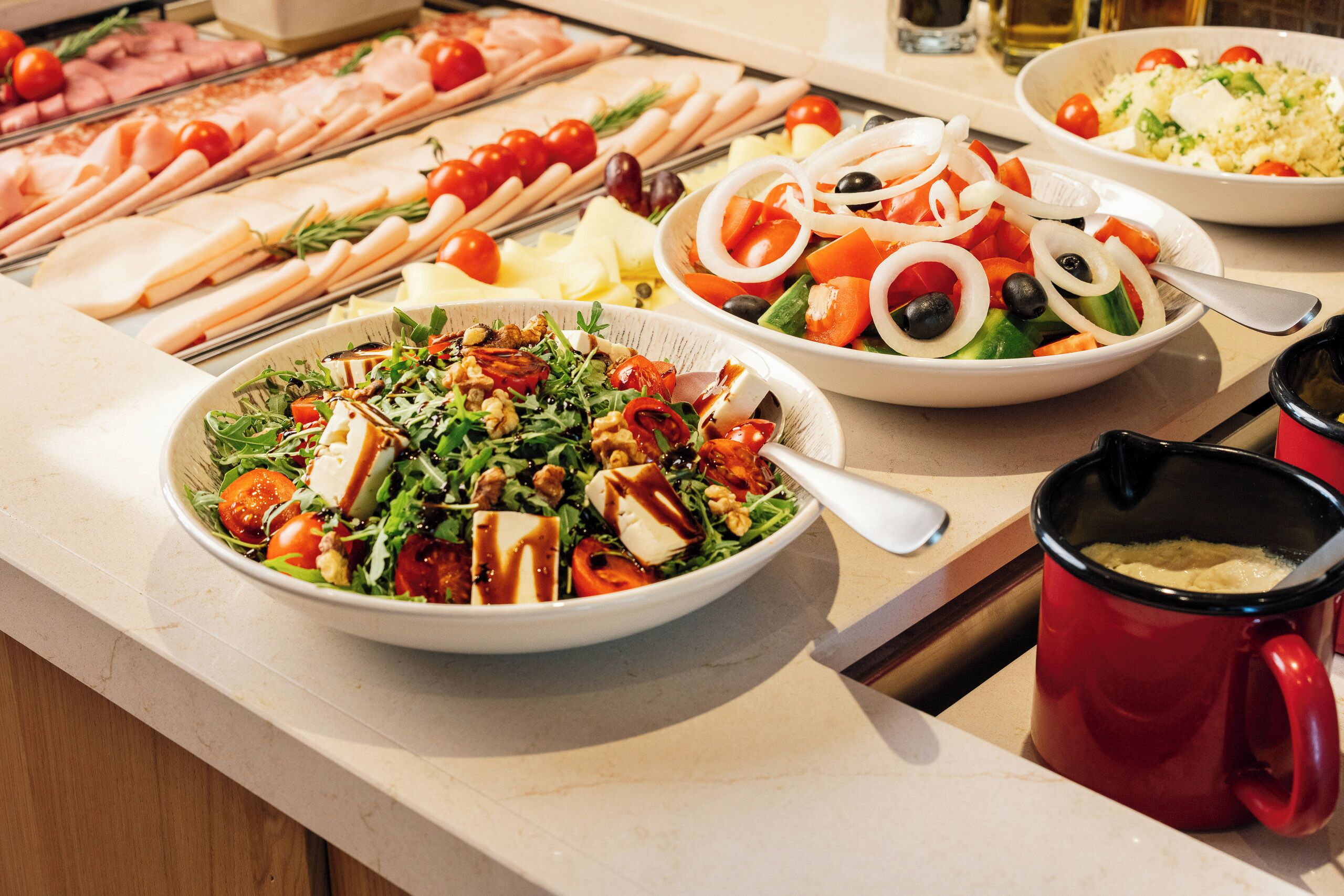 Ein Buffet mit verschiedenen Speisen, darunter Salate, Fleisch und Reis.