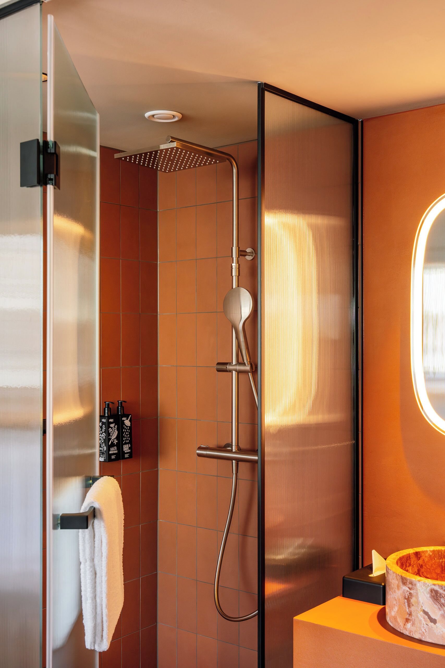 Un baño moderno con cabina de ducha de vidrio, un perchero y encimera de mármol.