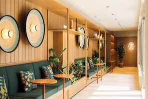 A modern interior with wooden paneling, green seating, and round tables. - Hotel Schani City (Vienna)