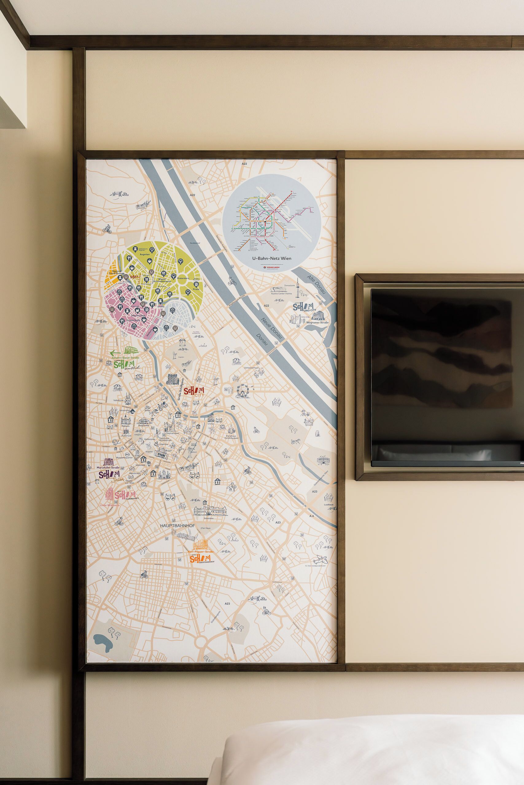 Un mapa urbano enmarcado con zonas resaltadas y un televisor en la pared.