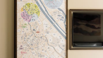 Un mapa urbano enmarcado con zonas resaltadas y un televisor en la pared.