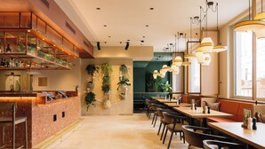 A restaurant with a bar area, seating, and hanging plants.