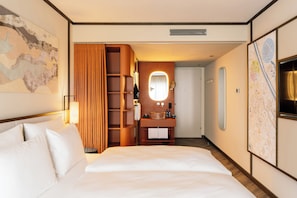 A hotel room with a bed, a vanity with a mirror, a map on the wall, and a wooden wardrobe. - Hotel Schani City (Vienna)