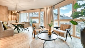 Ein modernes Interieur mit Essbereich, Sofas und großen Fenstern mit Blick auf eine verschneite Landschaft.