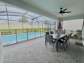 A covered patio area with a pool, a table with chairs, and a ceiling fan. - The Lovely Retreat near Disney w/ pool ! (Four Corners)