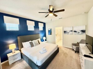 A bedroom with a large bed, a ceiling fan, a desk, and a chair. - The Lovely Retreat near Disney w/ pool ! (Four Corners)