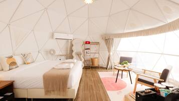 A modern, spacious room with a large bed, a desk, and a chair.
