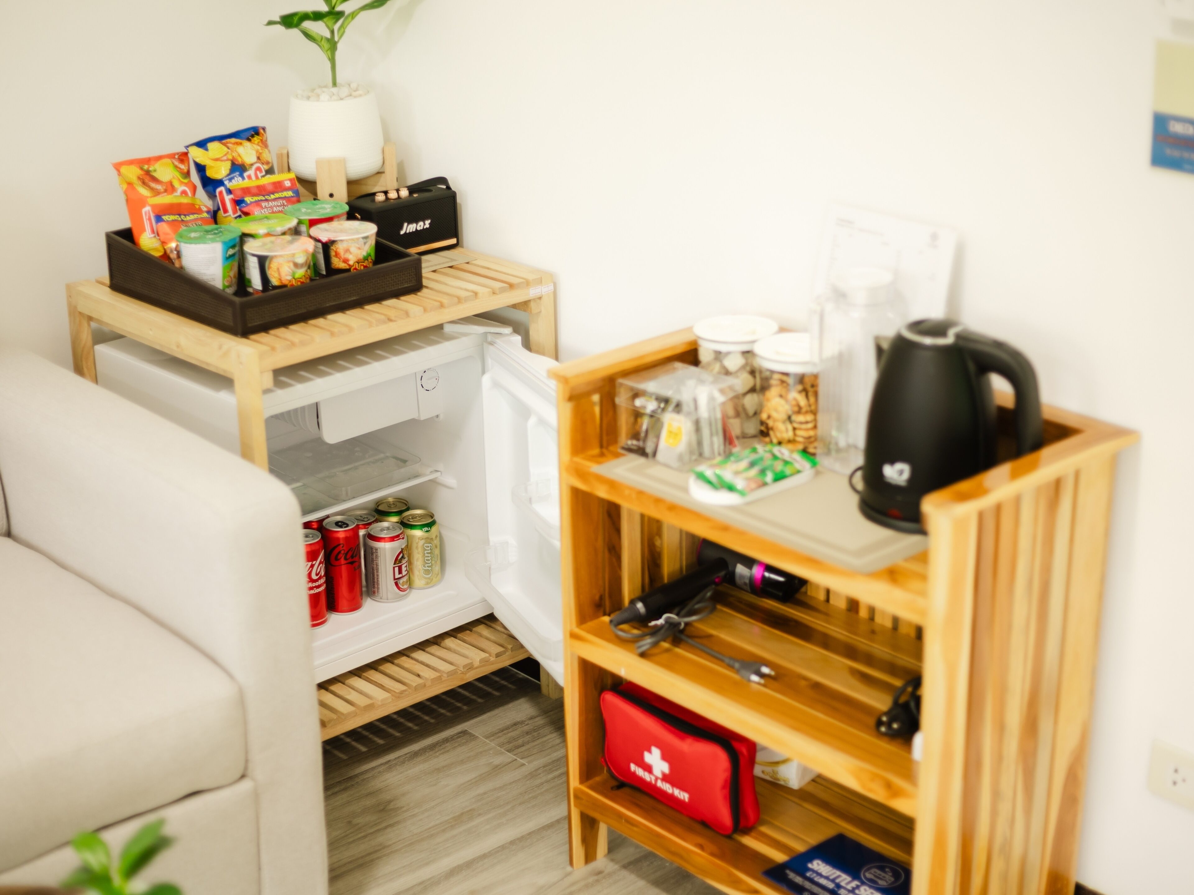 Une petite cuisine équipée d’un réfrigérateur, d’une machine à café et d’une étagère contenant des collations et des boissons.