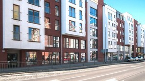 A multi-story residential building with a modern architectural design, featuring large windows and a mix of brick and white facades. - AS HOME Kosciuszki (Wrocław)