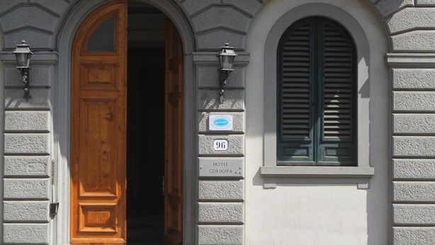 A hotel entrance with a wooden door, a window with shutters, and a sign indicating the hotel name and number. - hotel cordova (Florence)