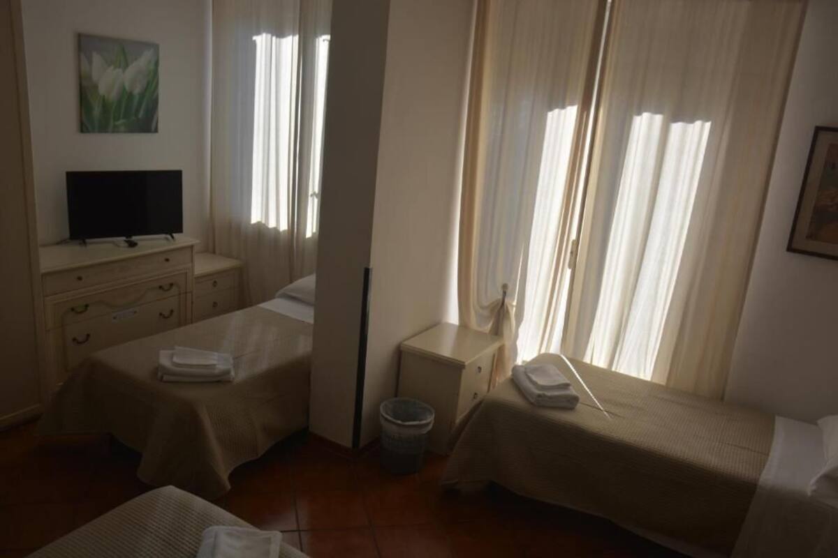 A hotel room with two beds, a television, a small table, and a trash bin.