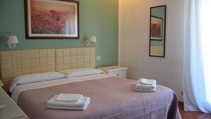 A hotel room with a large bed, two bedside tables, a nightstand, and a framed artwork on the wall. - hotel cordova (Florence)