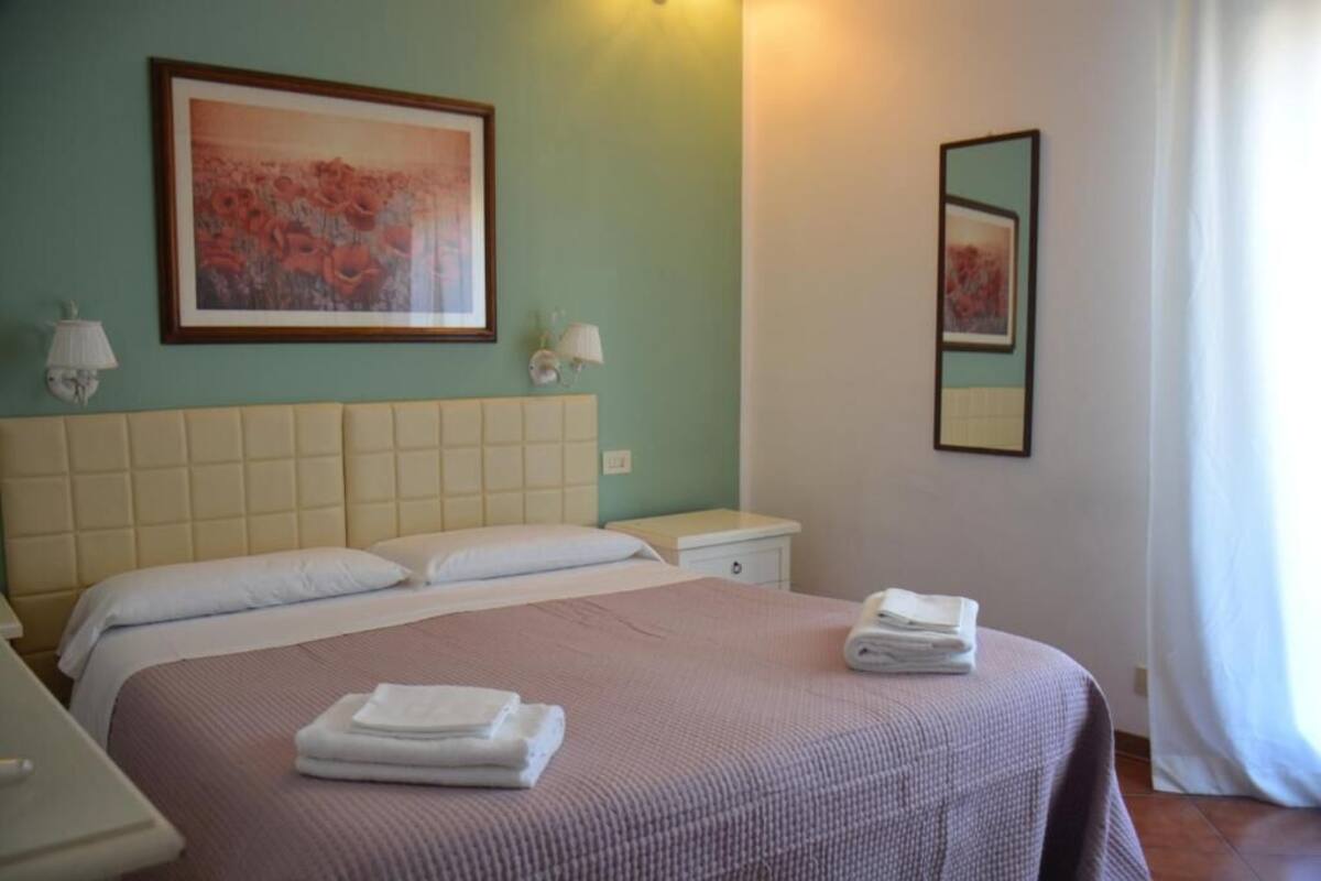 A hotel room with a large bed, two bedside tables, a nightstand, and a framed artwork on the wall.