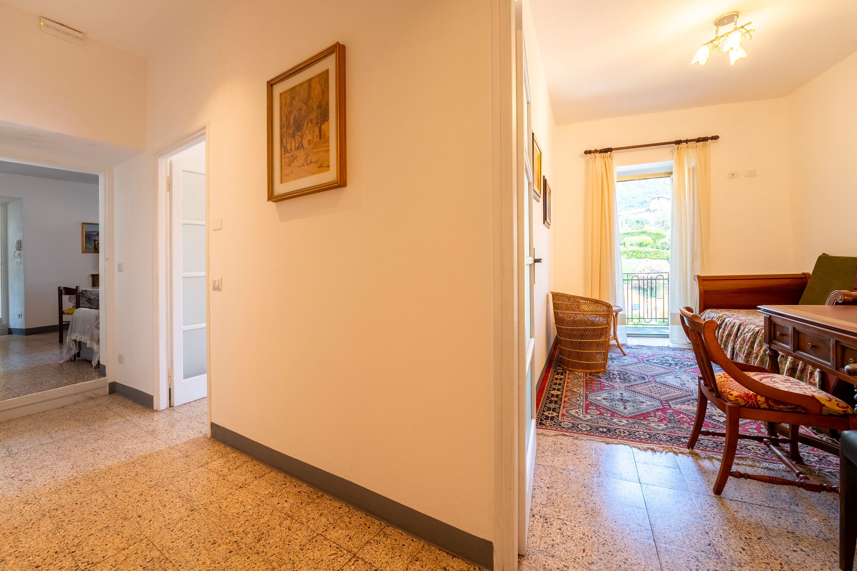 Un pasillo con comedor, una alfombra estampada y una silla de madera.