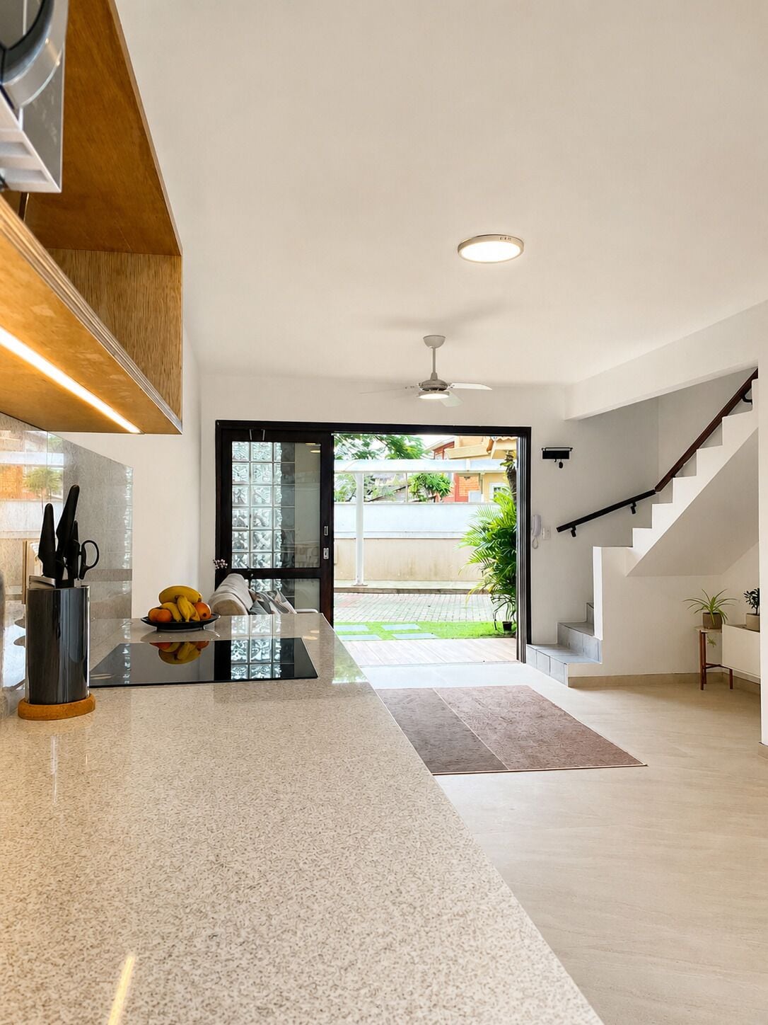 Una cocina moderna con una isla central, un área de comedor y una escalera que lleva a un nivel superior.