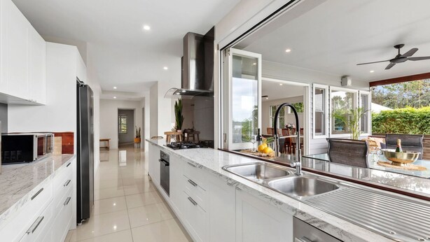 Una cocina moderna con una isla grande, electrodomésticos de acero inoxidable y vistas al área de comedor exterior.
