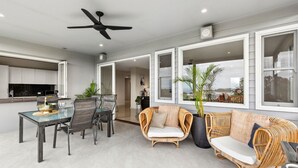 Un amplio espacio de estar con mesa de comedor, sillas, sofá y ventilador de techo.