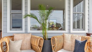 Un sofá de mimbre con una jardinera central y vistas al exterior a través de amplios ventanales.