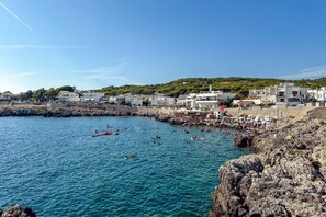 Un pueblo costero con edificios, costa rocosa y agua azul cristalina.