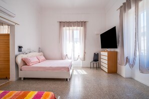 Een slaapkamer met een bed, een televisie, een bureau en een stoel.