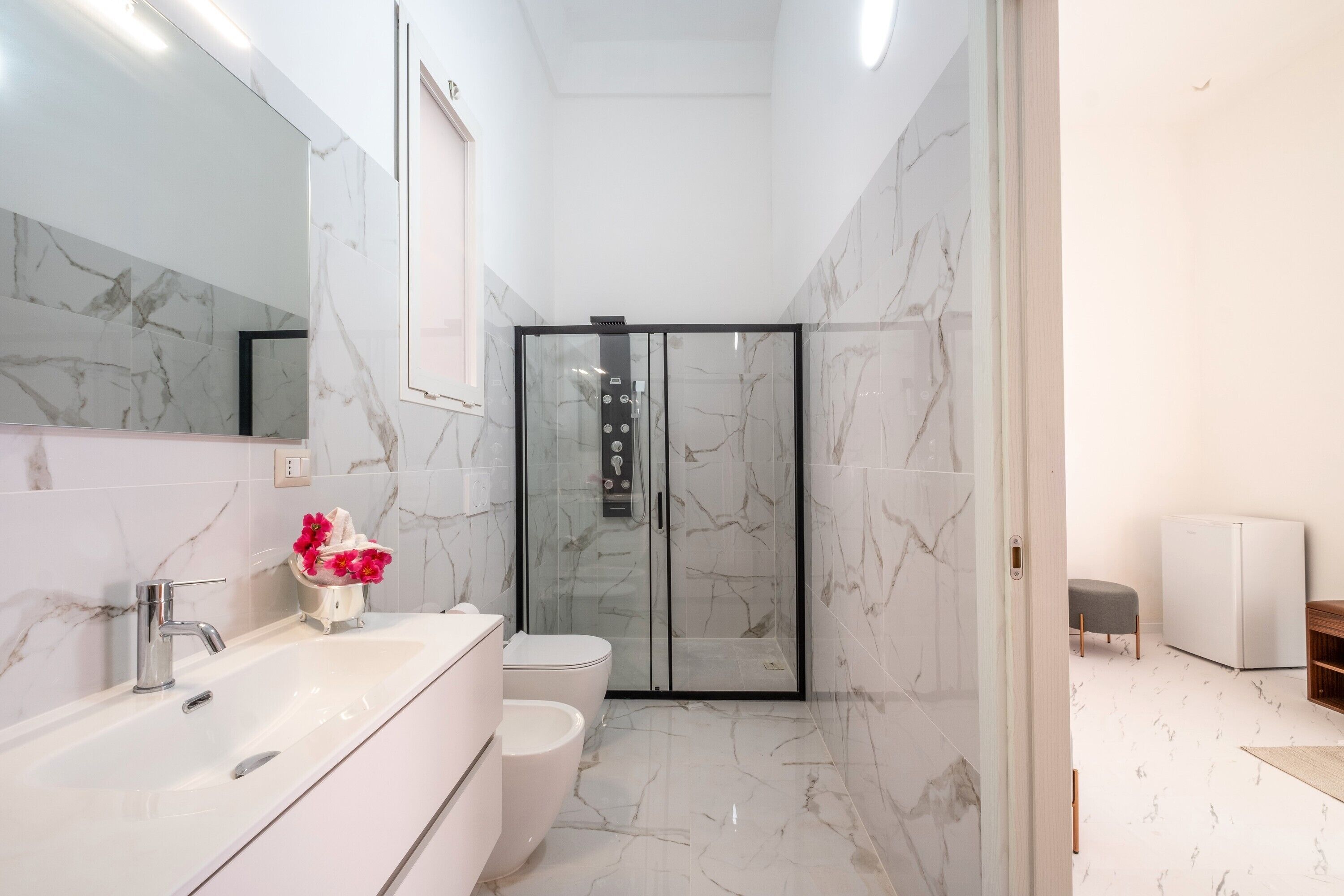 Um banheiro moderno com box de vidro, pia branca e vaso sanitário.