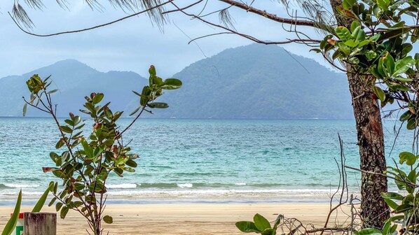 Una playa con vistas al océano y montañas al fondo.